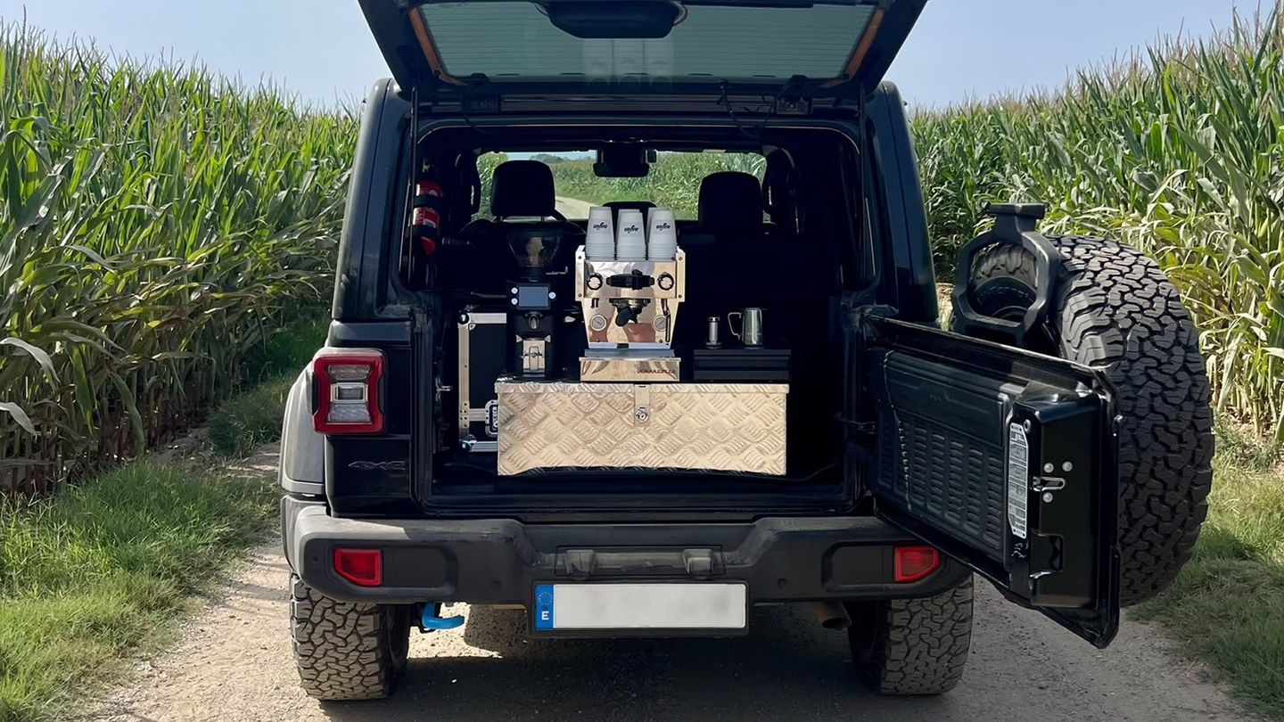 The nafen 4x4 parked on a dirt track between maize fields, tailgate open, with an espresso machine and grinder set up in the back.